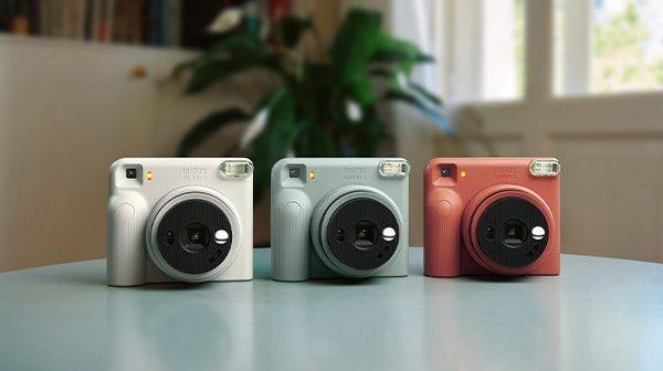 The instax SQUARE 2 in Misty White, Slate Blue and Brick Red, photographed side by side. The three colours are the full launch range.