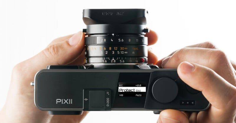 A Pixii digital rangefinder in hand, showing the top plate display that replaces the conventional rear screen arrangement.